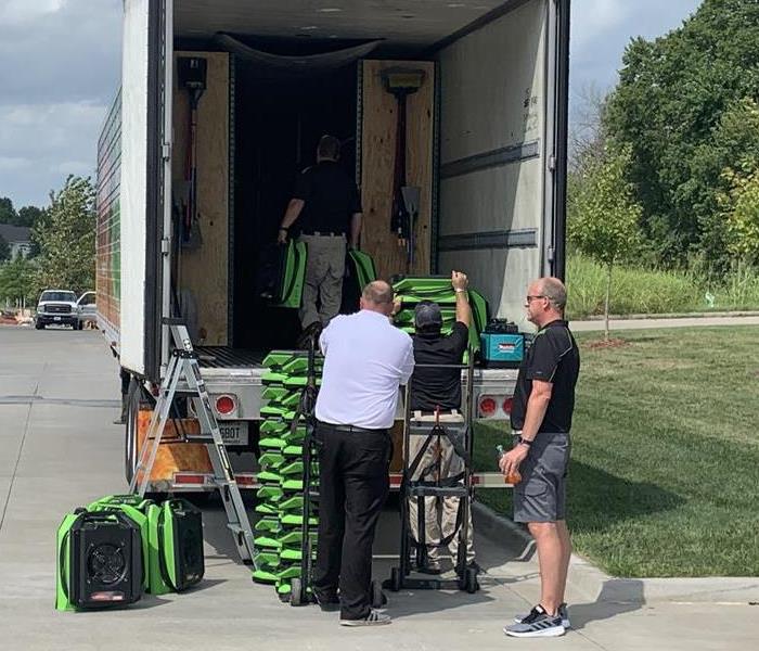 a team of guys unloading green air movers from a semi truck